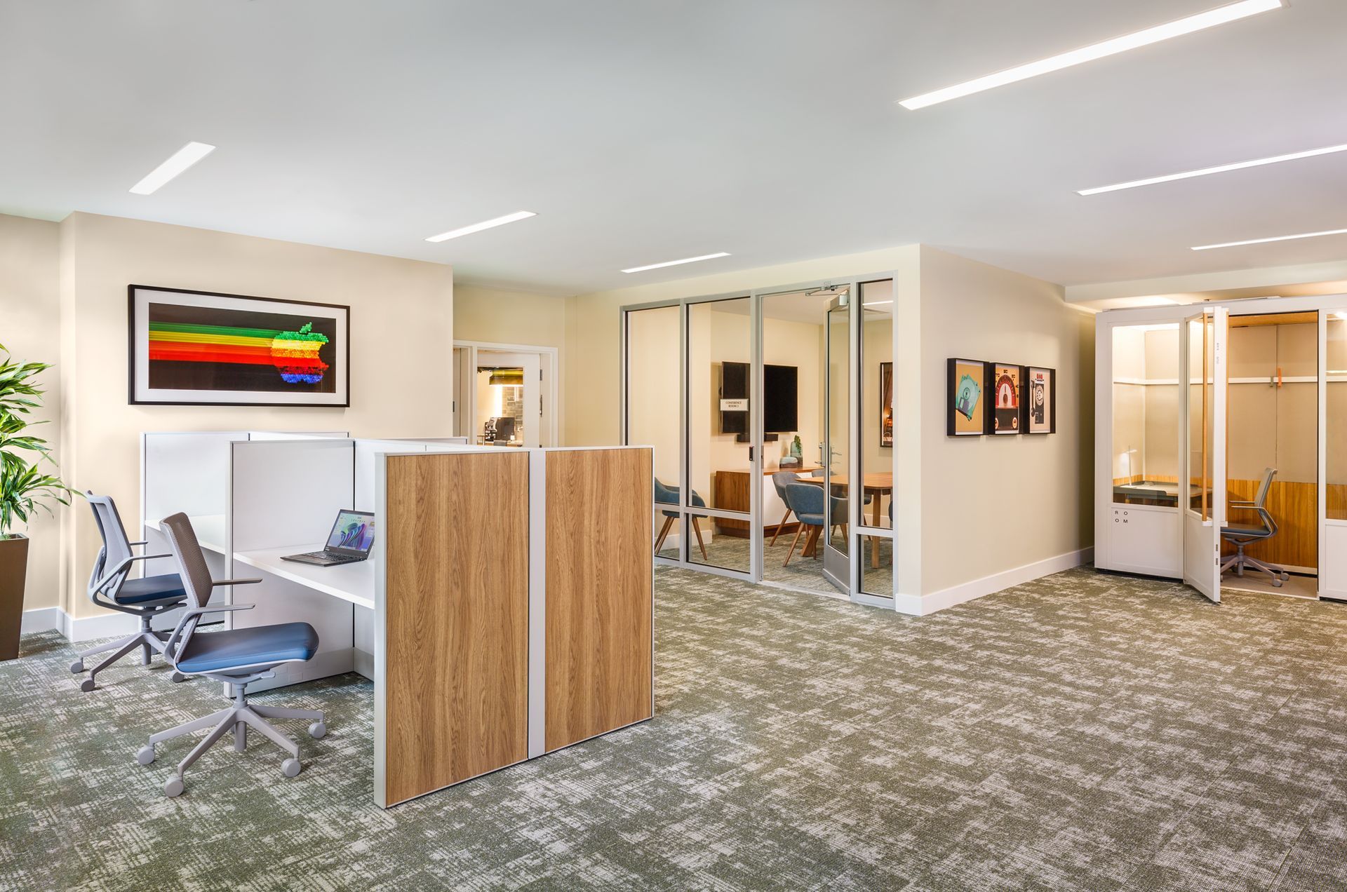 Modern office space with cubicles, conference room, and abstract art.