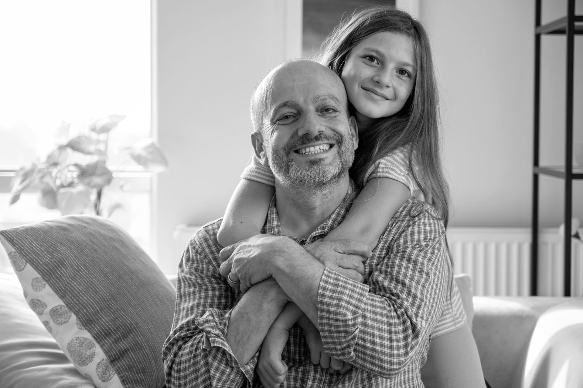 A little girl is hugging a man on a couch. A little girl is hugging a man on a couch.