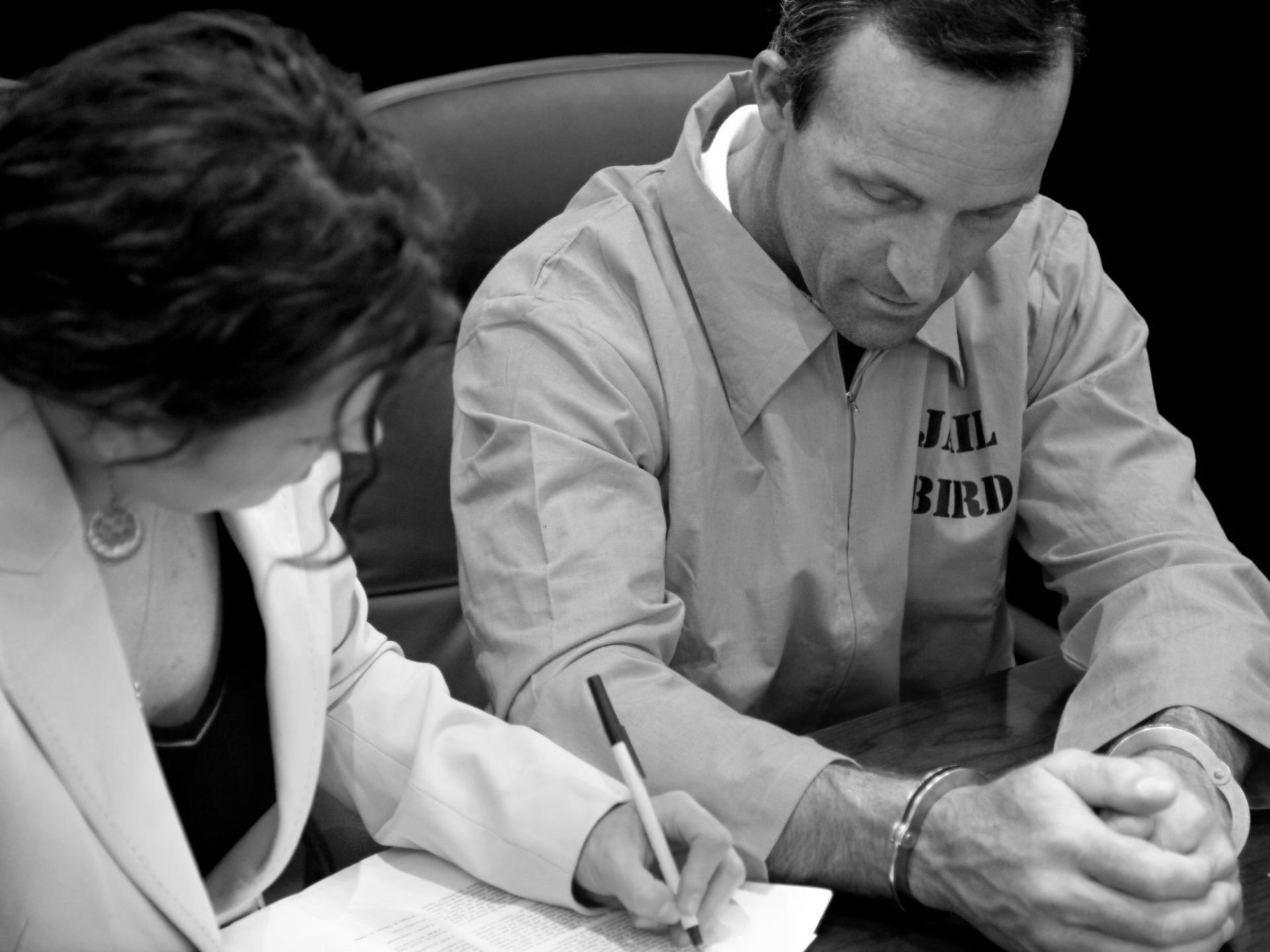 A man in an orange jailbird uniform is signing a document A man in an orange jailbird uniform is signing a document