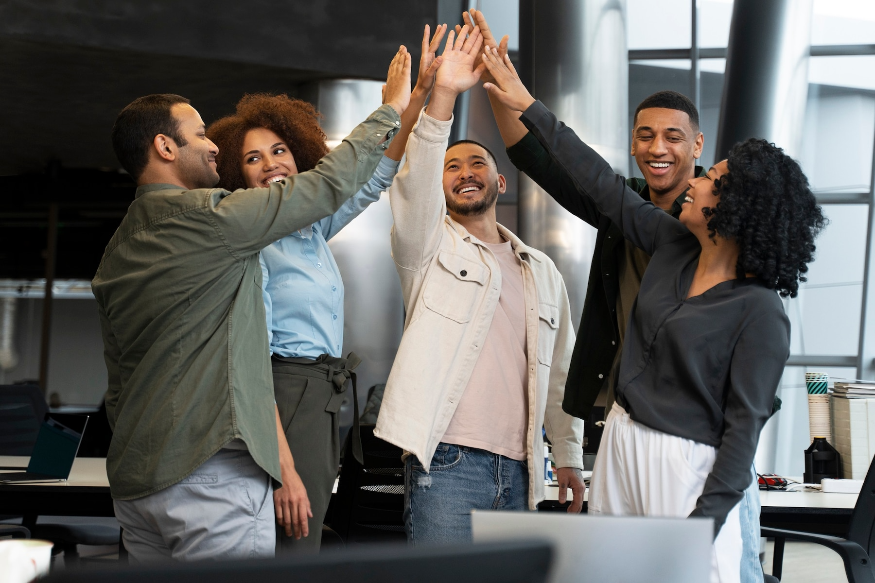 A group of people are giving each other a high five in an office.