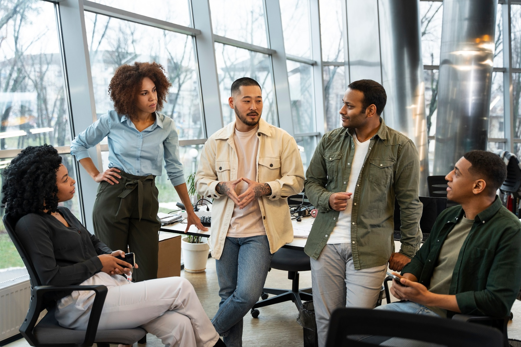 A group of people are standing around talking in an office.