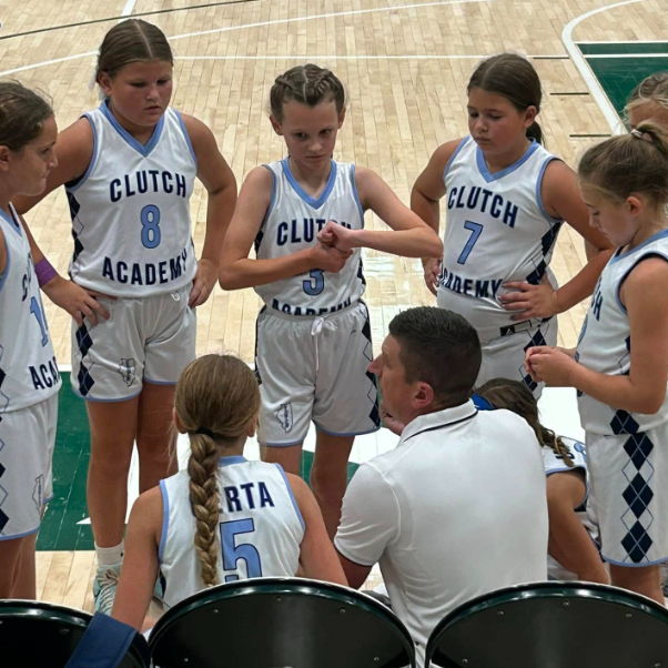 Girls’ basketball team huddled around coach during a timeout on the court