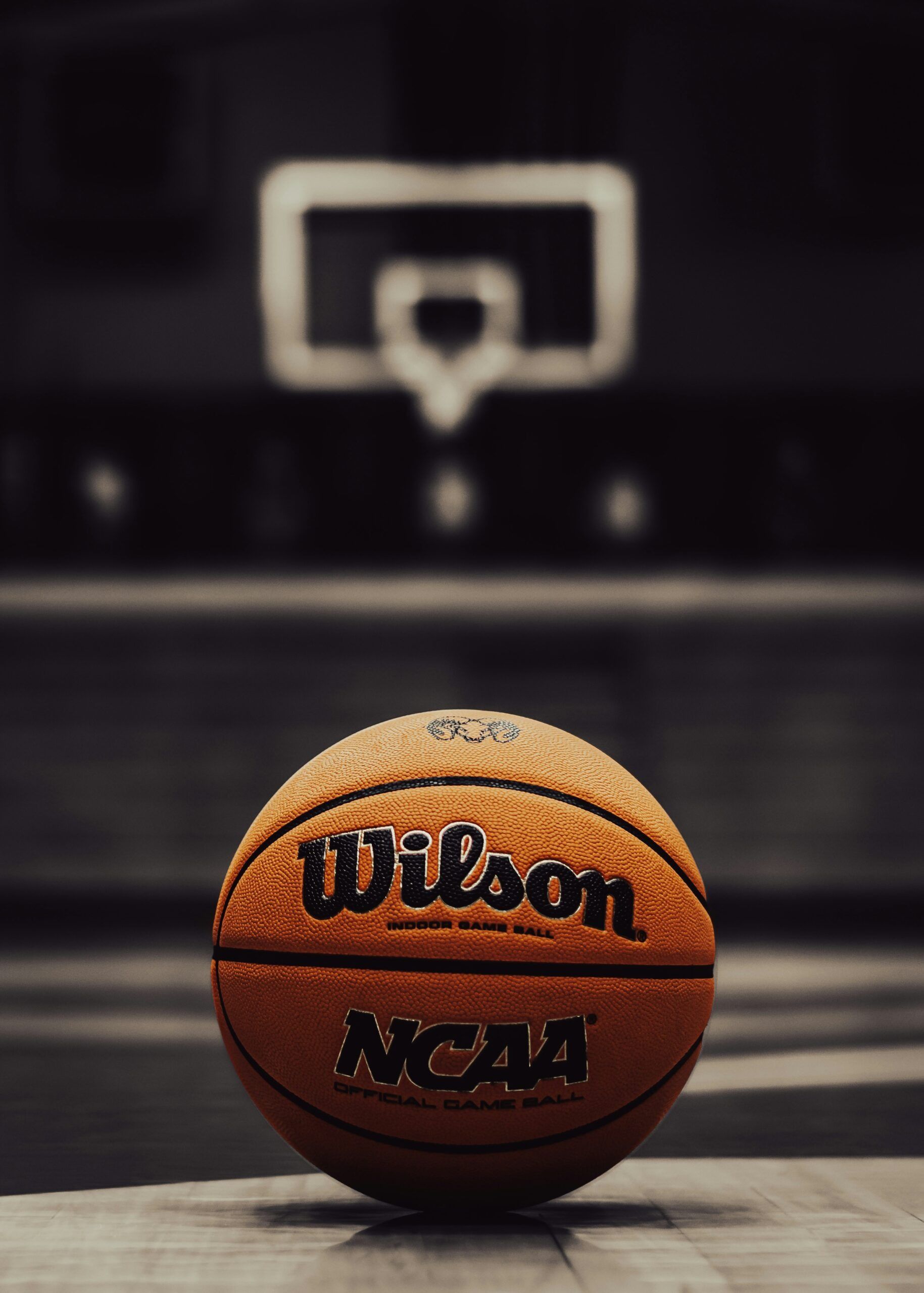 Wilson NCAA basketball on a court with a blurred hoop in the background
