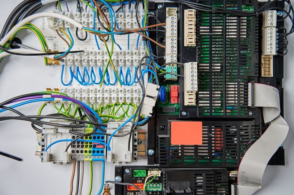 Panel with an array of electrical wiring, terminals, and circuit boards. Blue, green, and white wires.