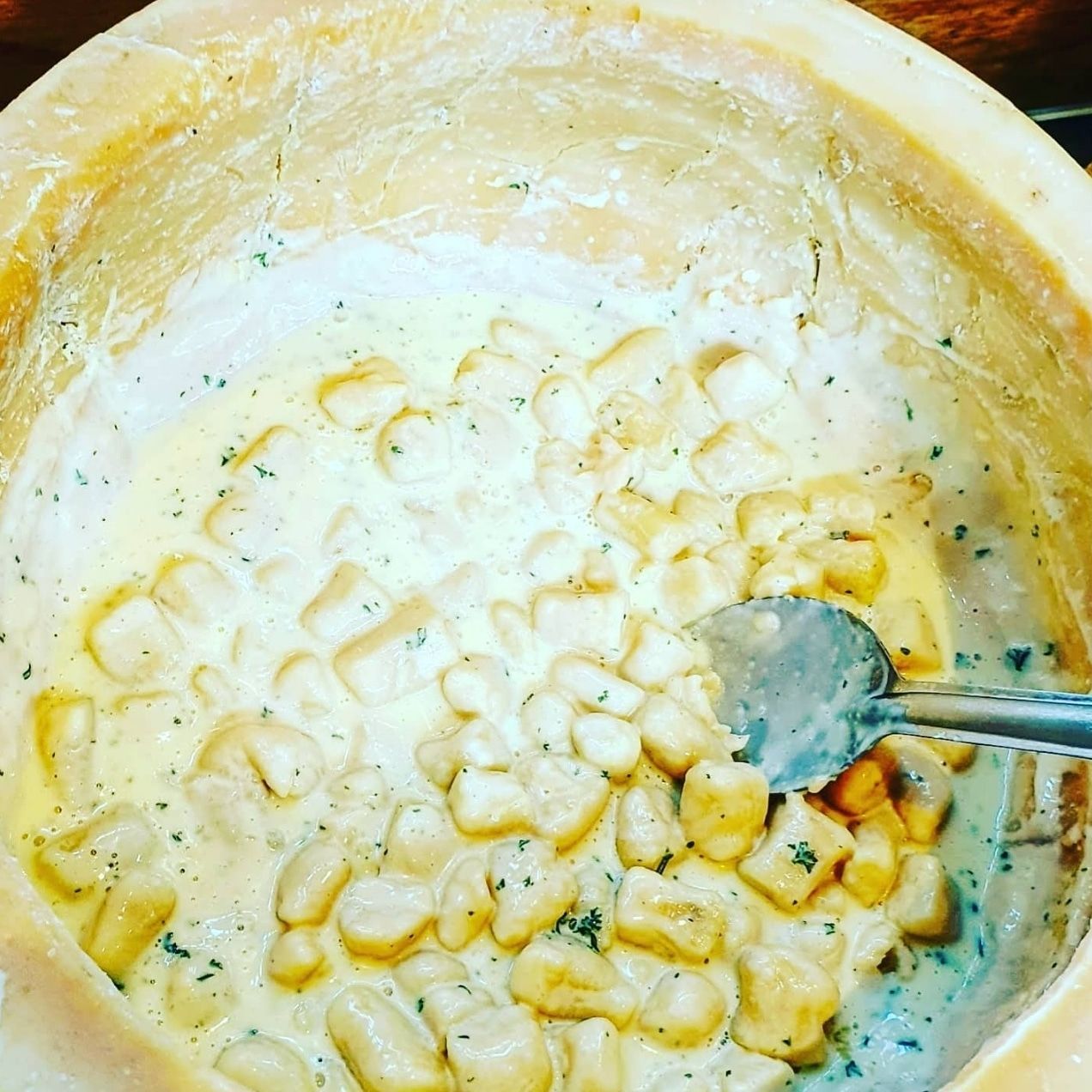 Handmade potato gnocchi being finished inside the Pasta Face Parmesan cheese wheel