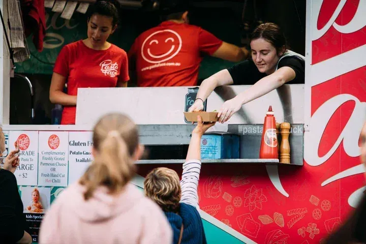 Pasta Face team handing freshly prepared food to a guest from the mobile kitchen service window