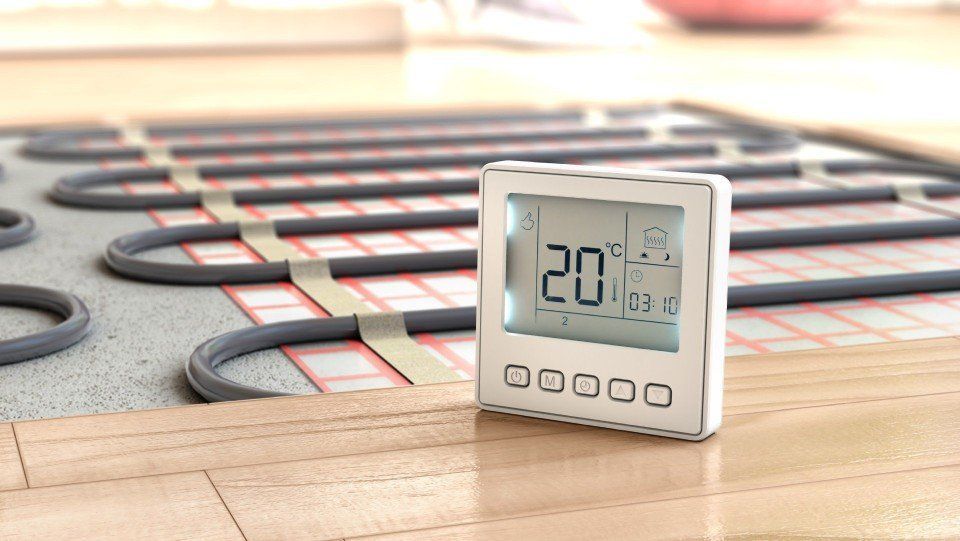 Termostato digitale a pavimento con serpentine di riscaldamento a pavimento rosse luminose in un interno domestico