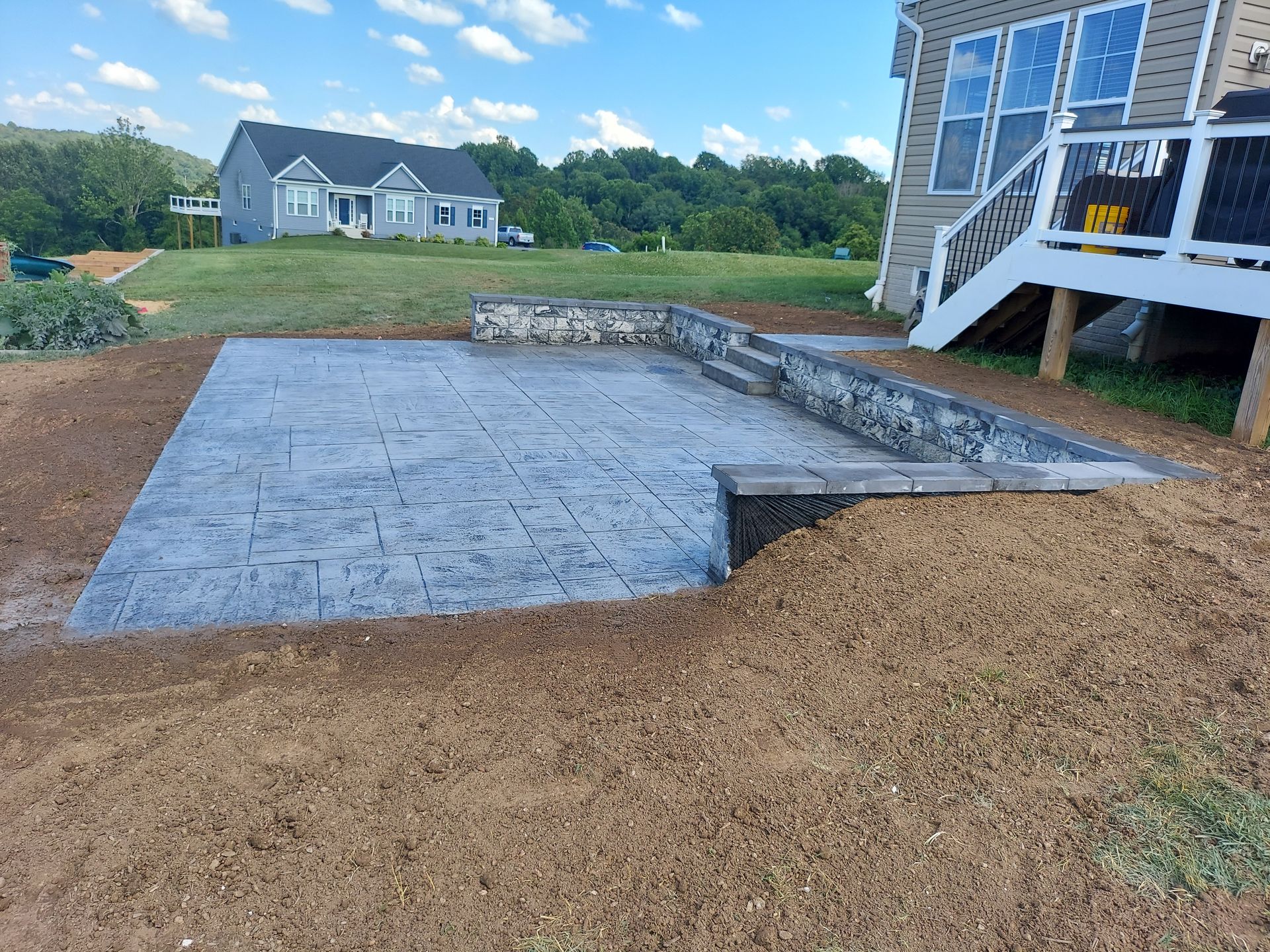 A patio with a staircase leading to a deck in front of a house.