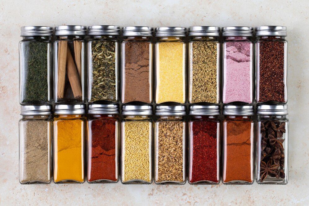 Une rangée de bocaux en verre remplis de différents types d'épices