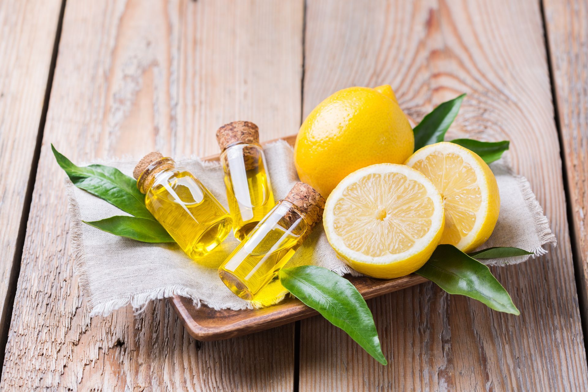Citrons et bouteilles d'huile essentielle sur une table en bois.