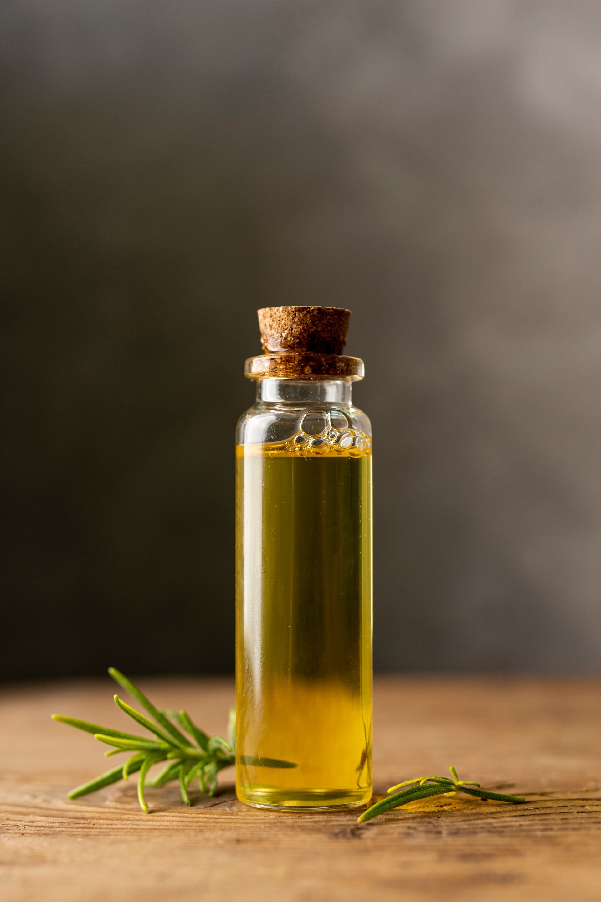 Une petite bouteille d'huile d'olive avec un bouchon sur une table en bois.