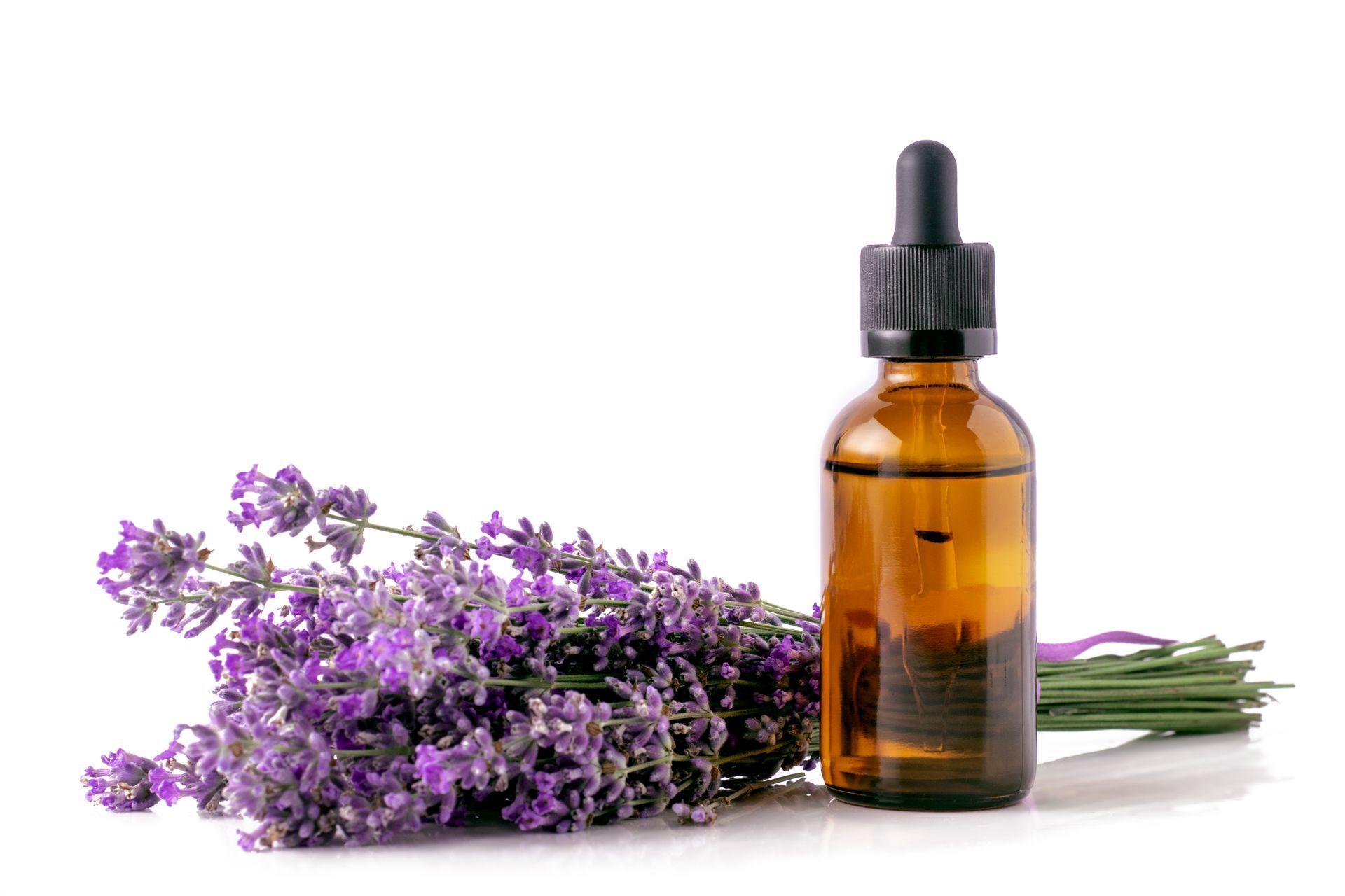 Une bouteille d'huile essentielle à côté d'un bouquet de fleurs de lavande.