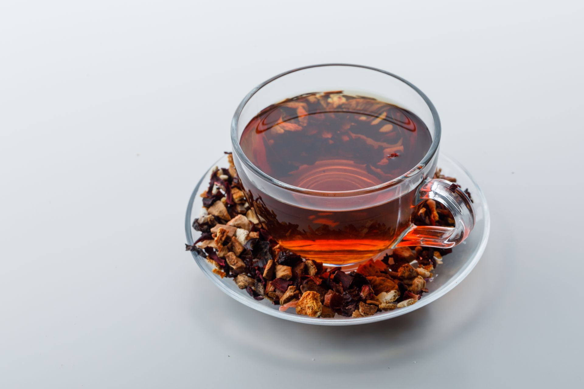 Une tasse de thé avec des fruits secs sur une soucoupe sur une table.