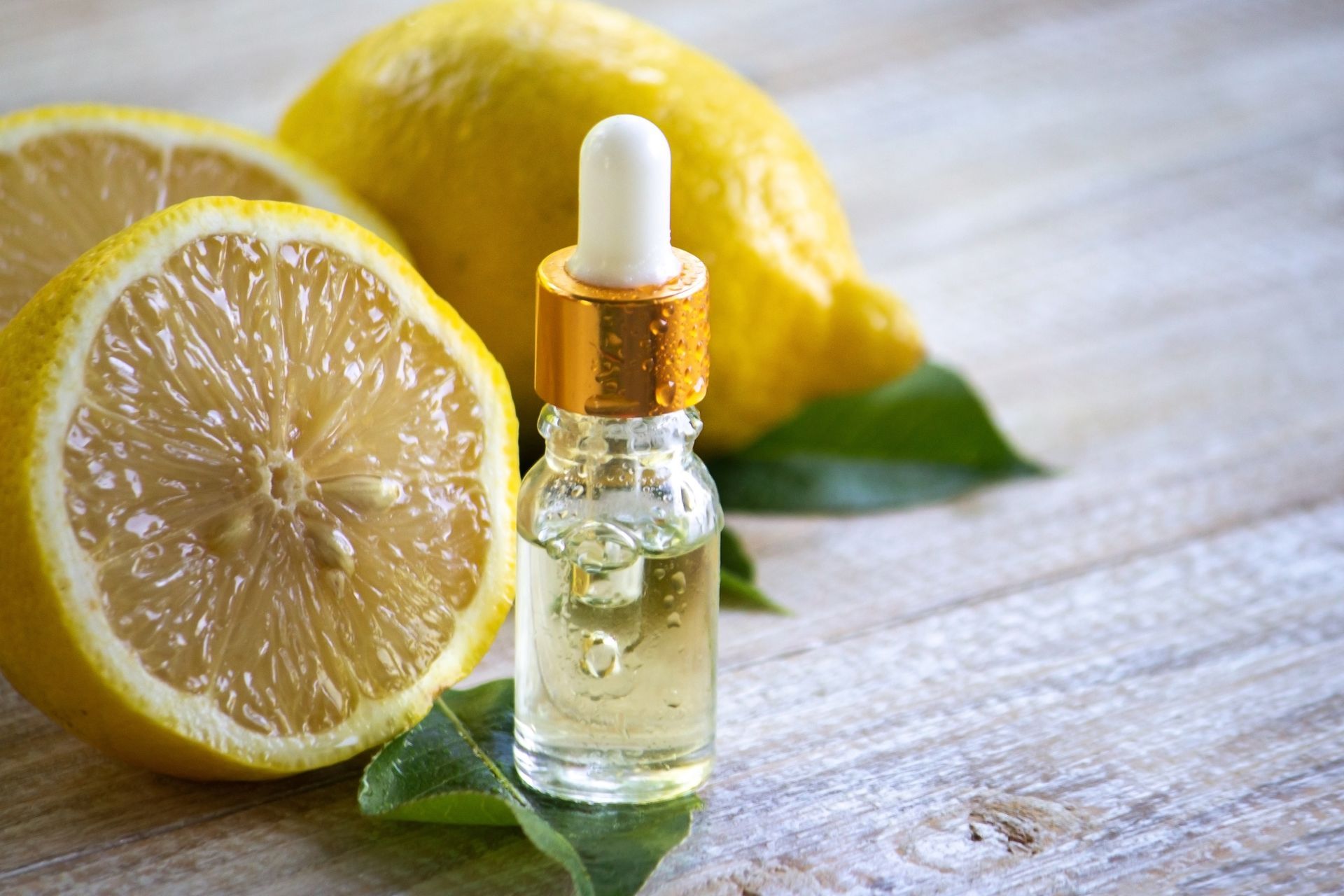 Une bouteille d'huile essentielle à côté de citrons sur une table en bois.