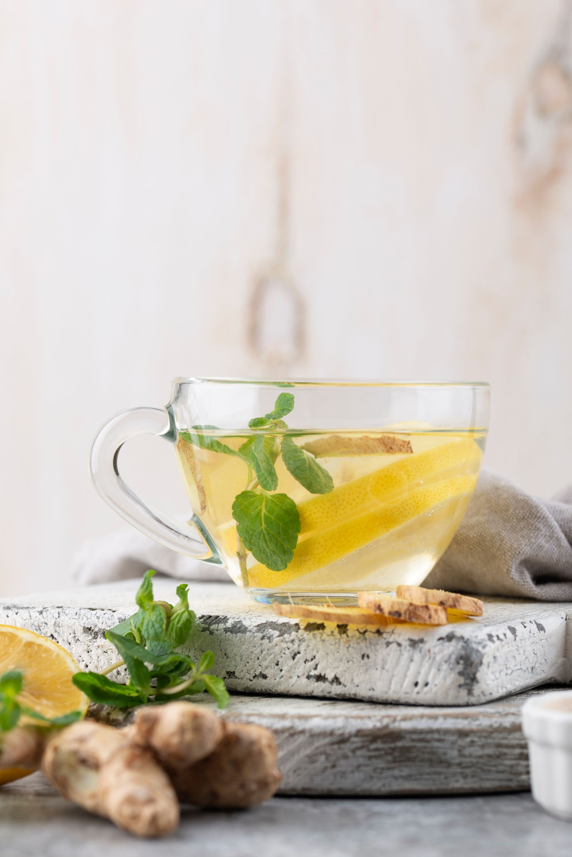 Une tasse de thé au gingembre avec des tranches de citron et des feuilles de menthe.