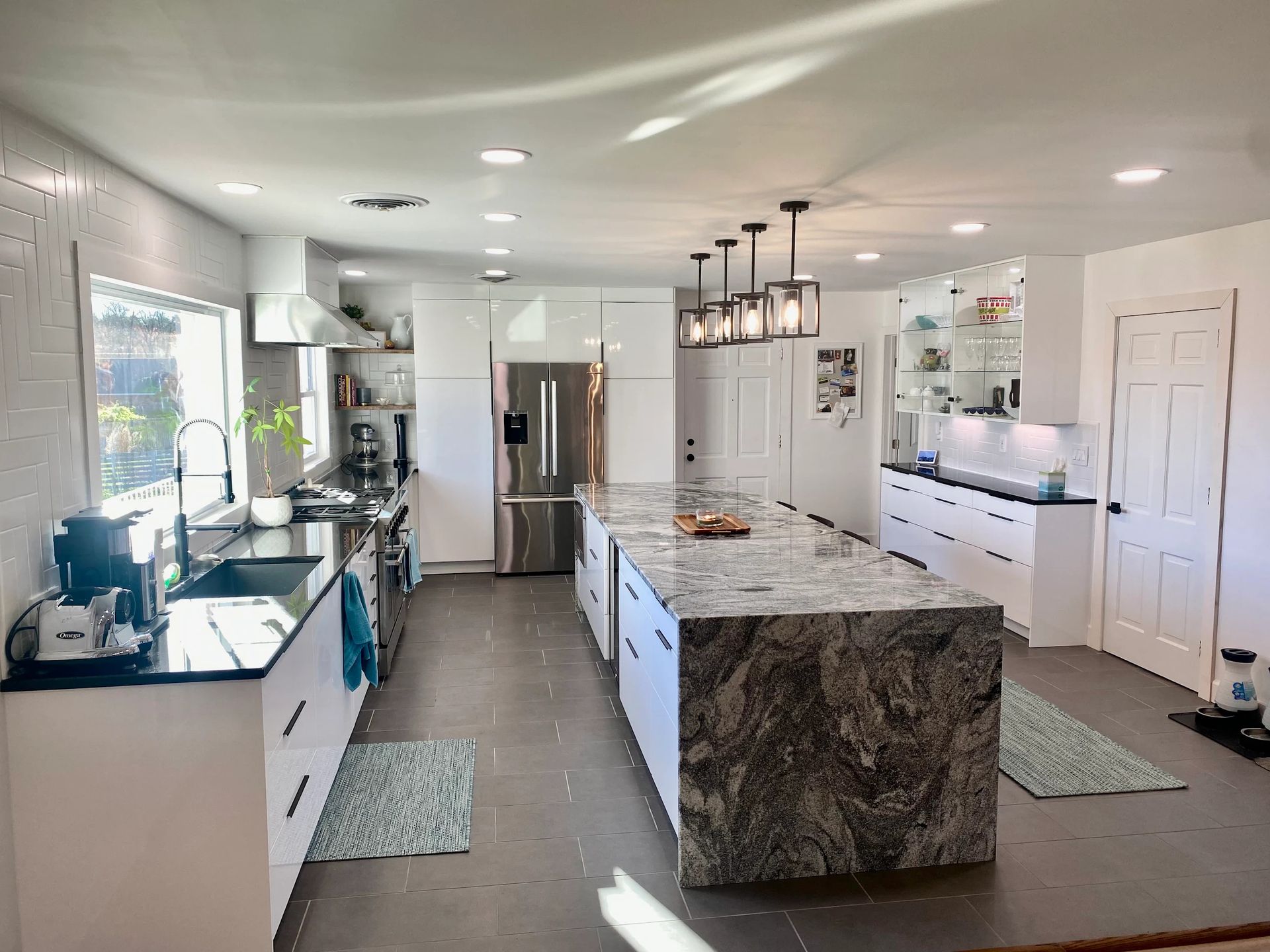 Bright modern kitchen with a granite island, white cabinets, stainless appliances, and pendant lights, by N. Edwards Enterprises