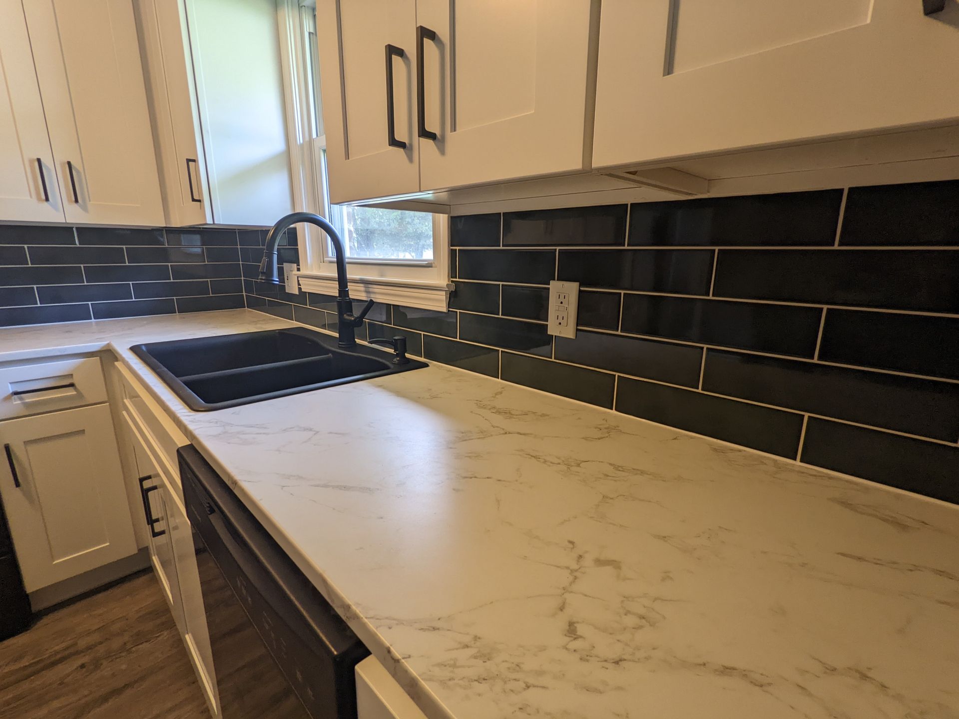 Modern kitchen with white cabinets and black subway tile backsplash.