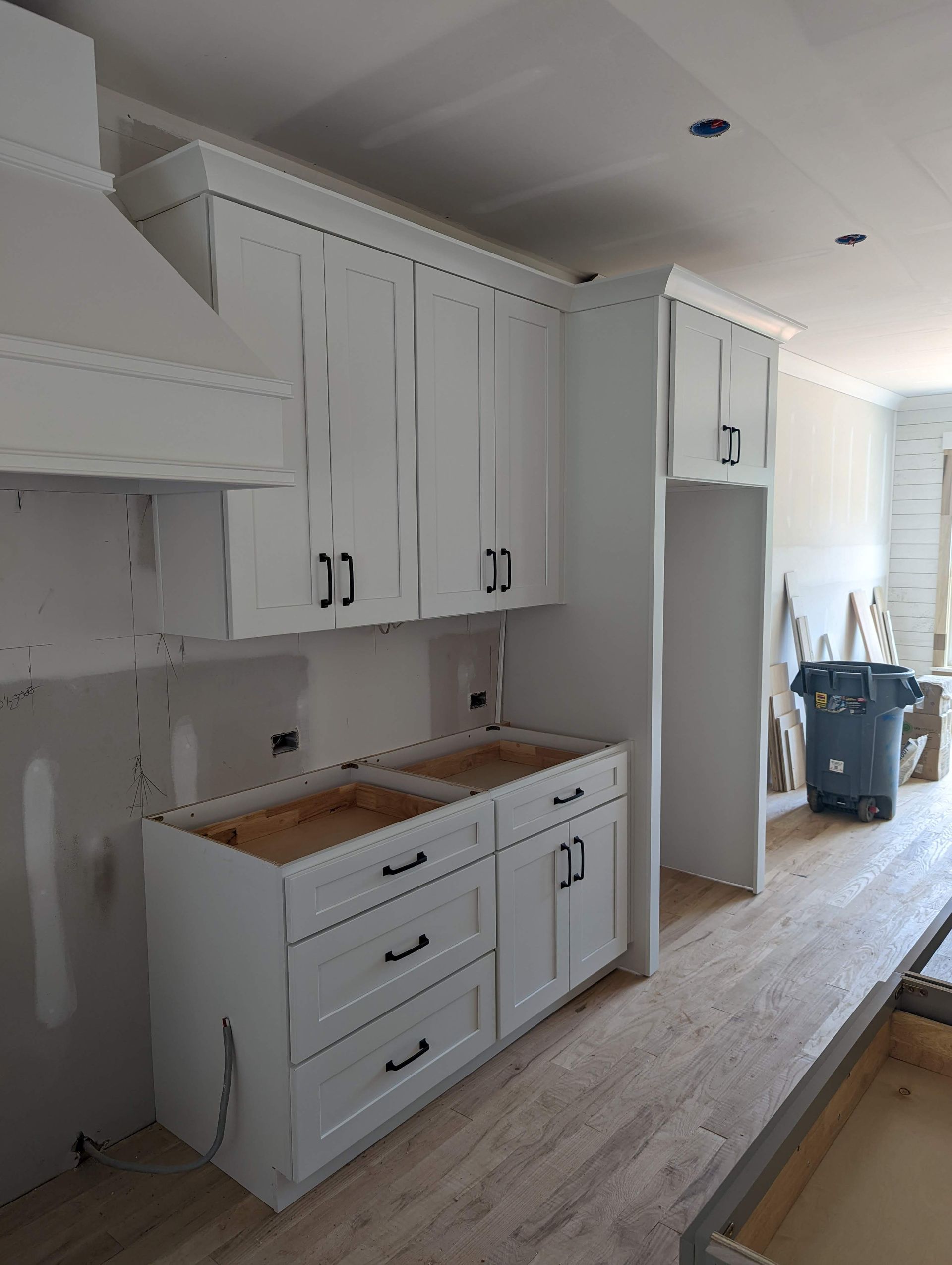 White kitchen cabinets with black hardware during construction.