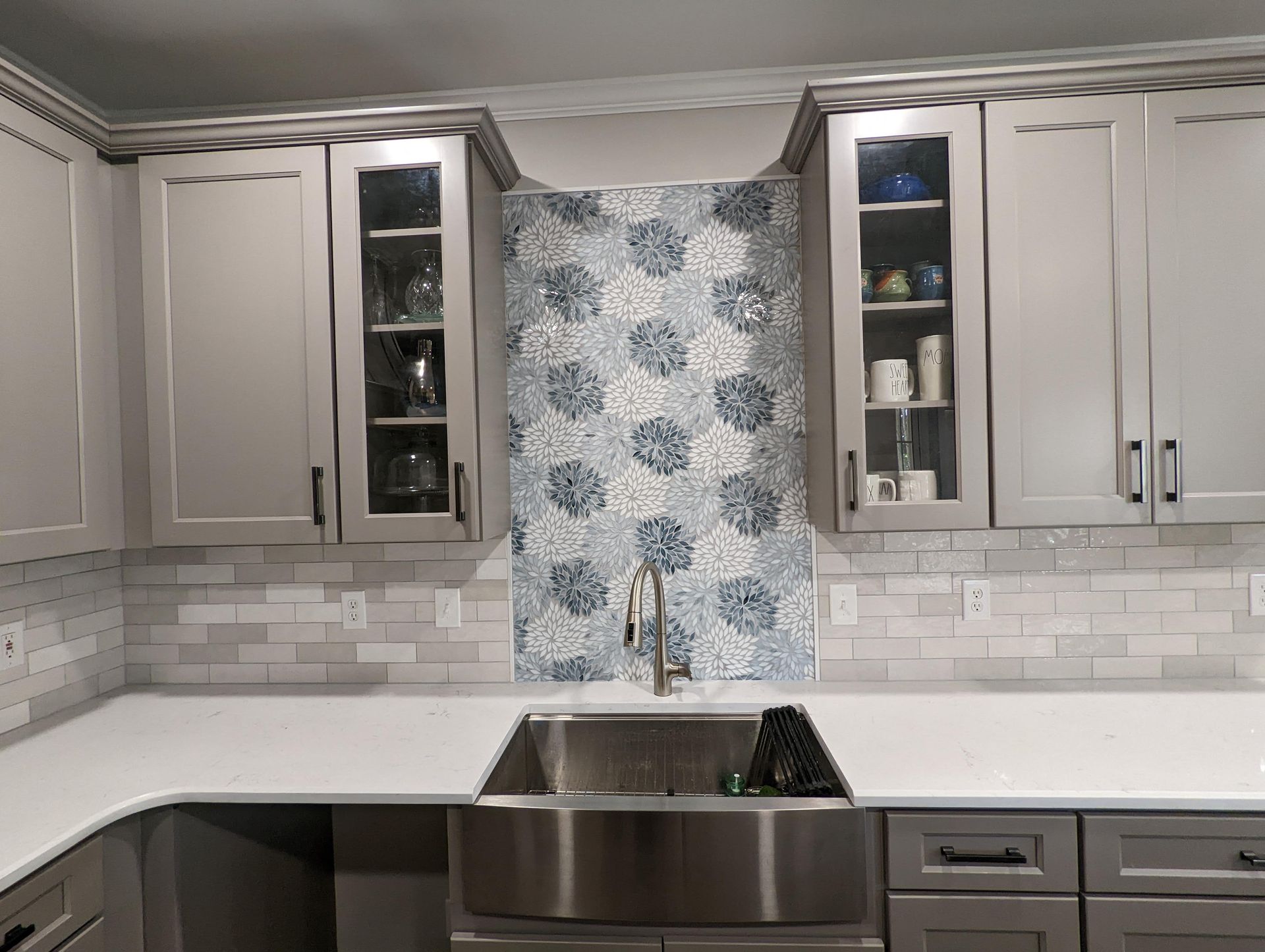 Kitchen with gray cabinets, white countertops, and patterned backsplash.