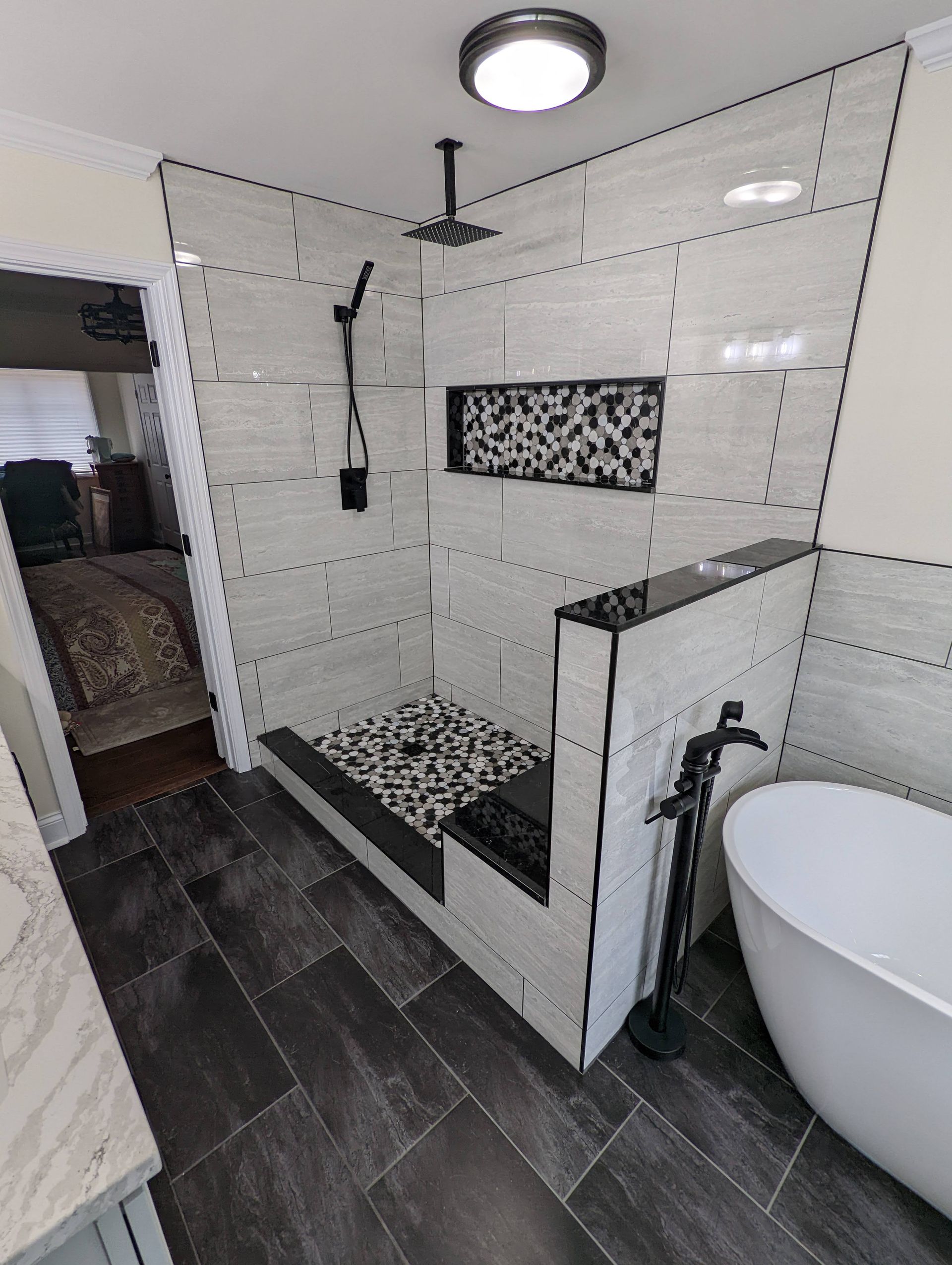 Modern bathroom with walk-in shower, freestanding tub, and wood-look tile.