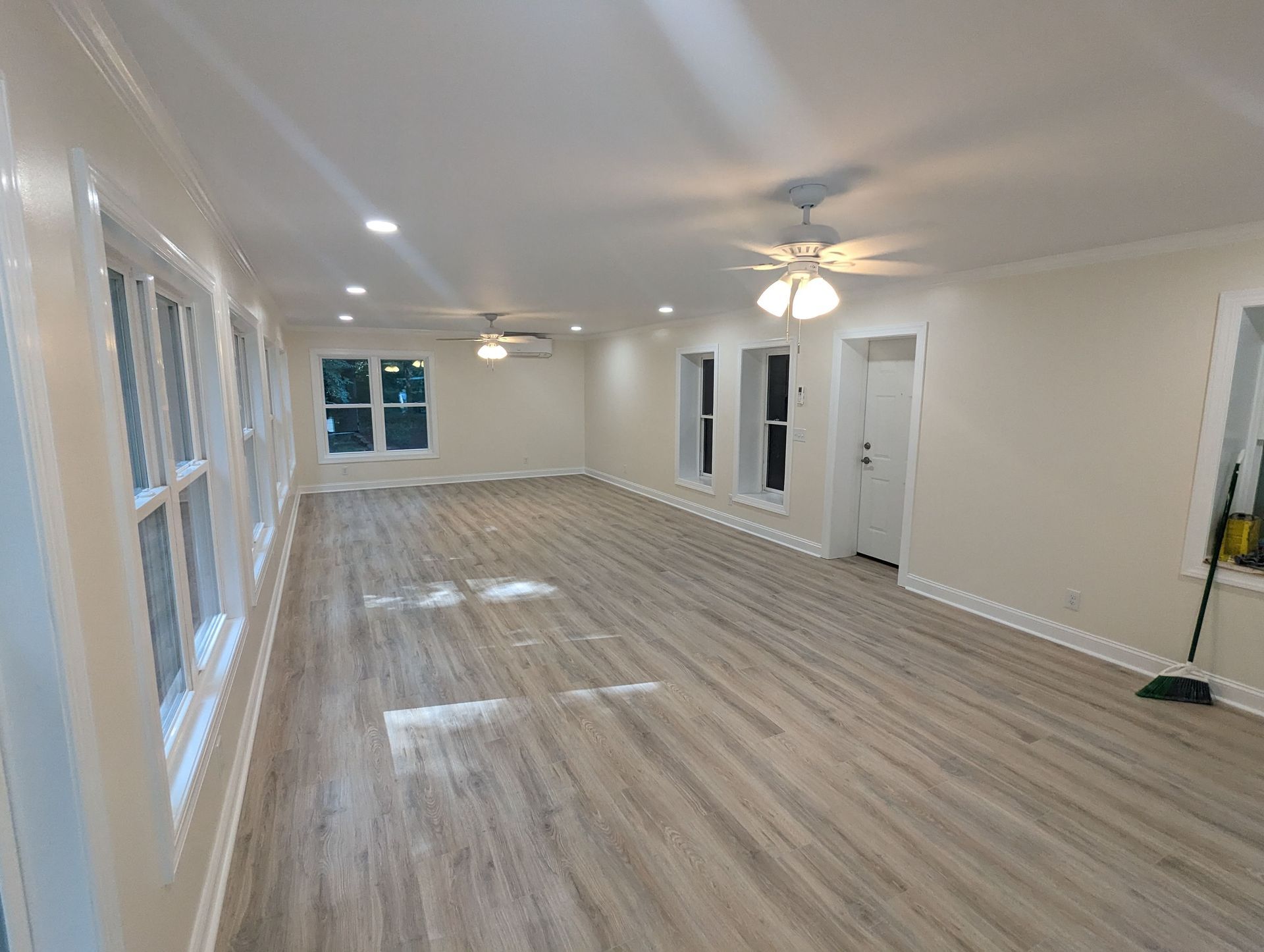 Large empty room with light wood flooring and white walls.