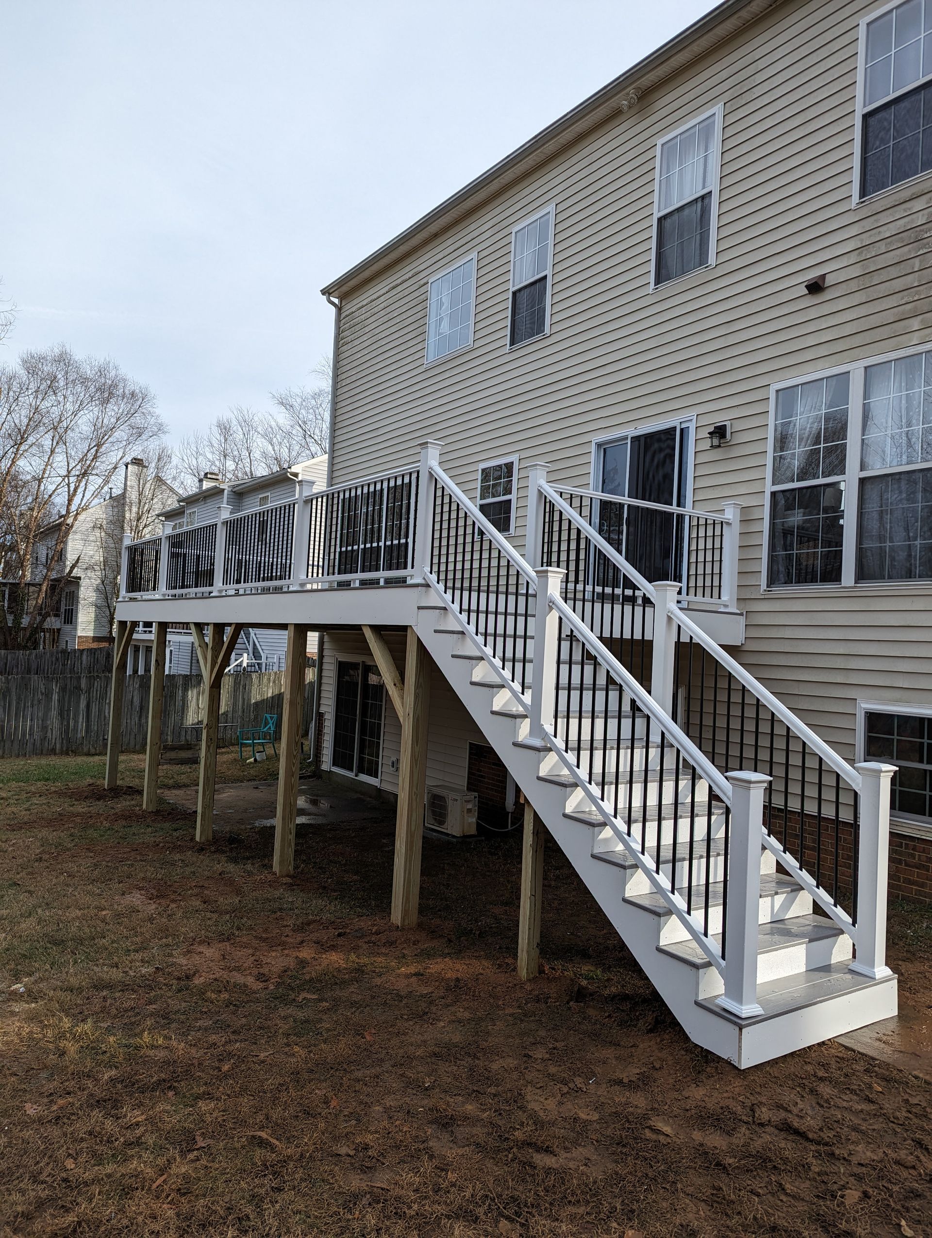 Elevated wooden deck with white railings attached to a two-story home.