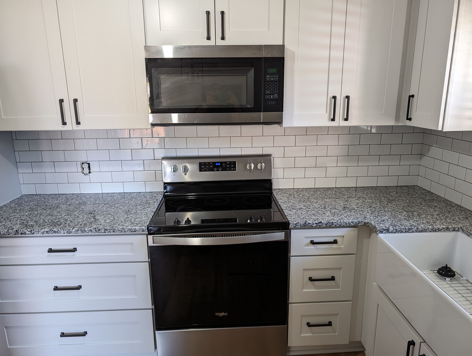Modern white kitchen with stainless steel appliances and subway tile backsplash.