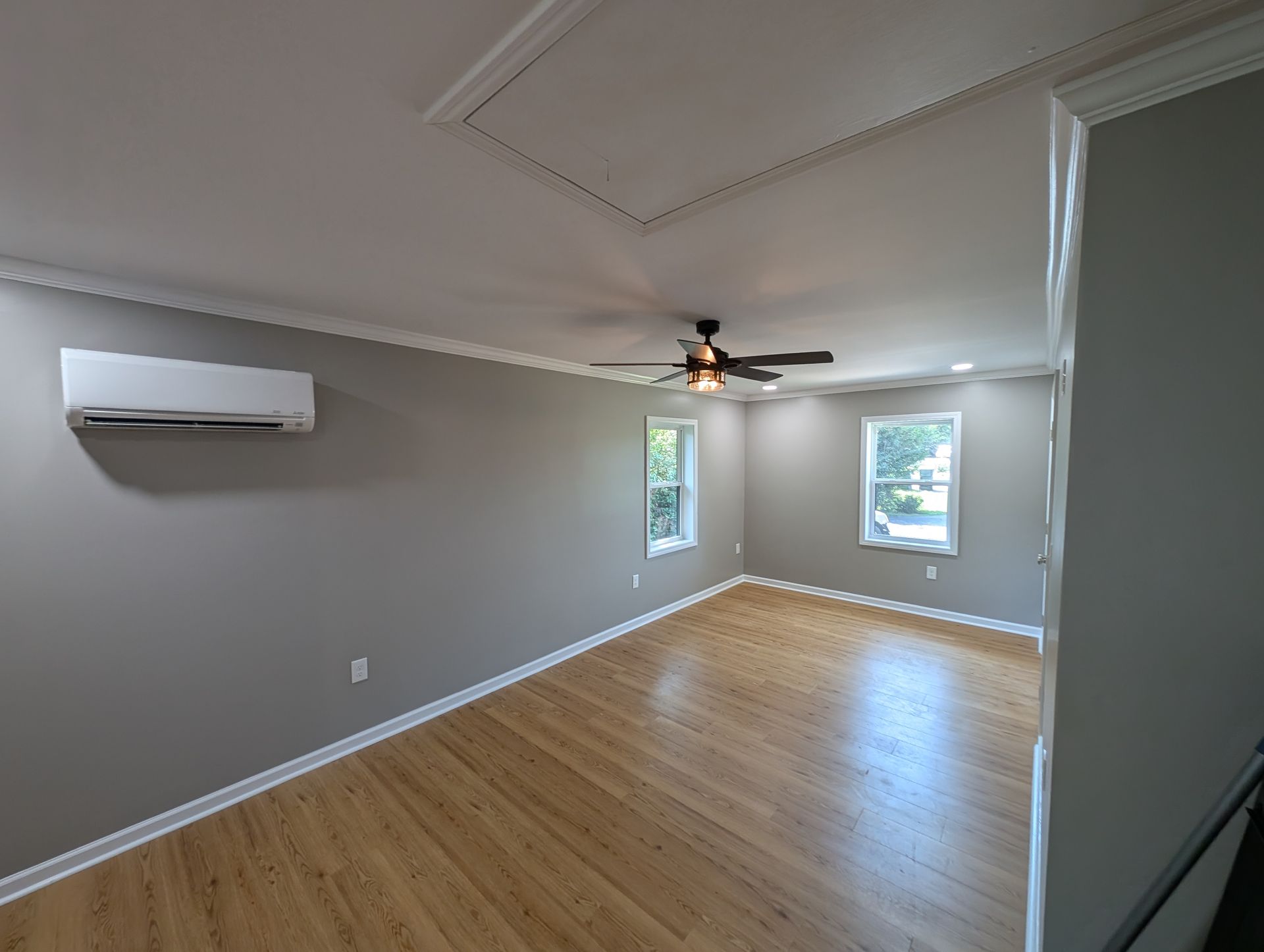 Room with hardwood floors, gray walls, and a ceiling fan.