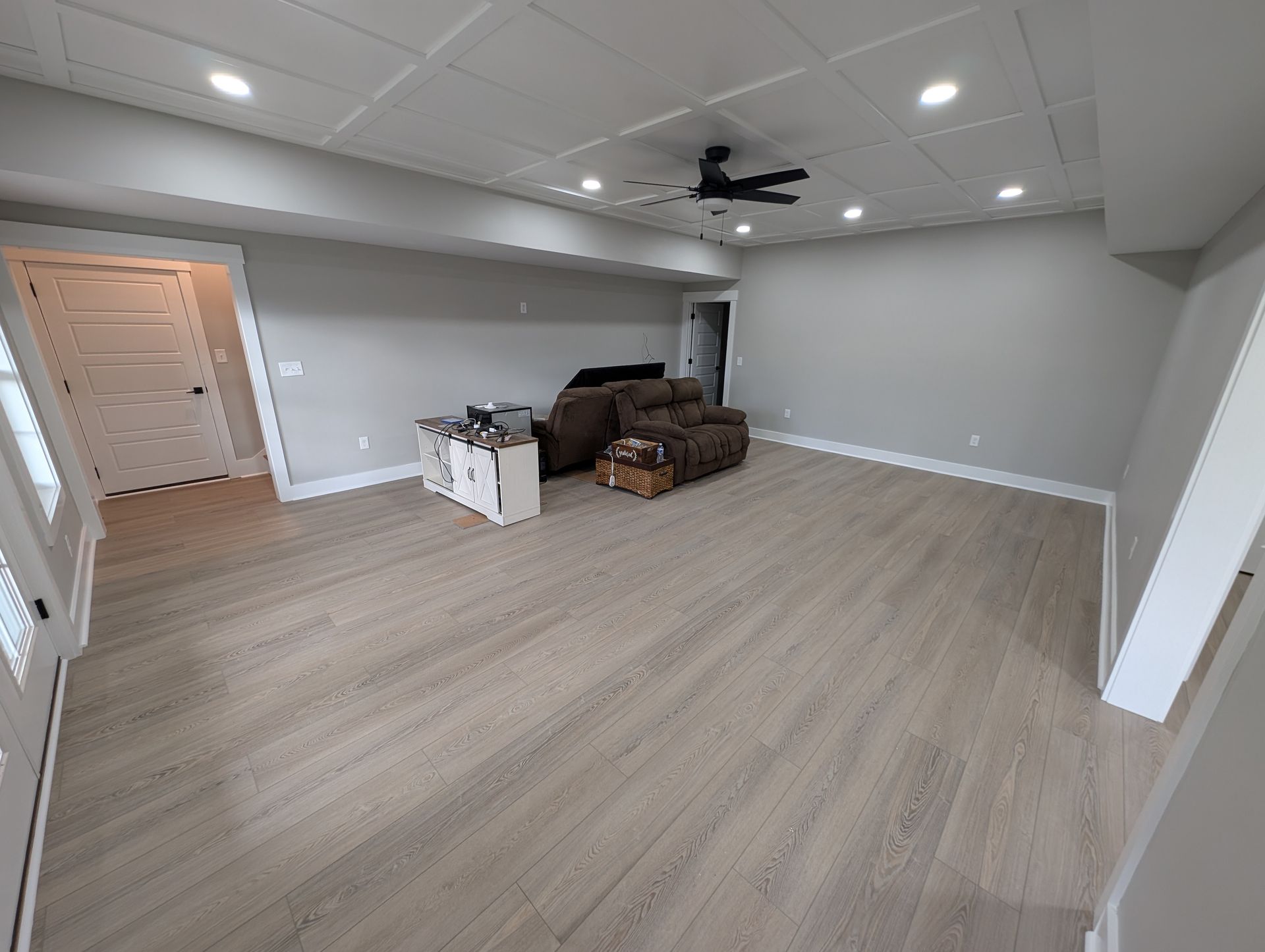 Spacious room with light wood-look flooring, gray walls, and recessed lighting.