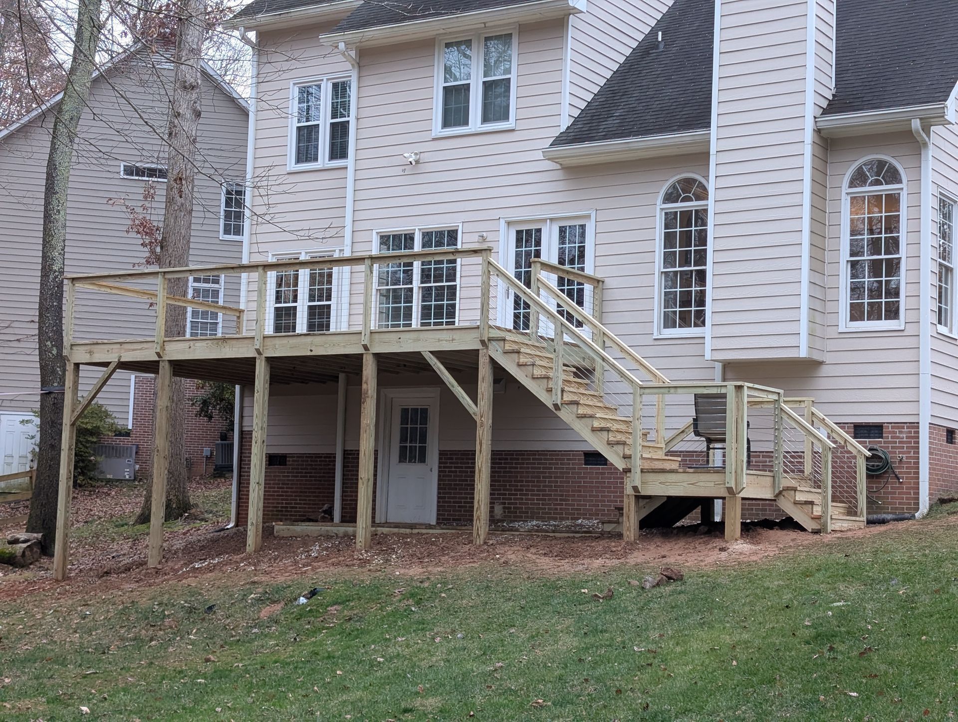 Back view of a two-story home with a wooden deck and stairs.