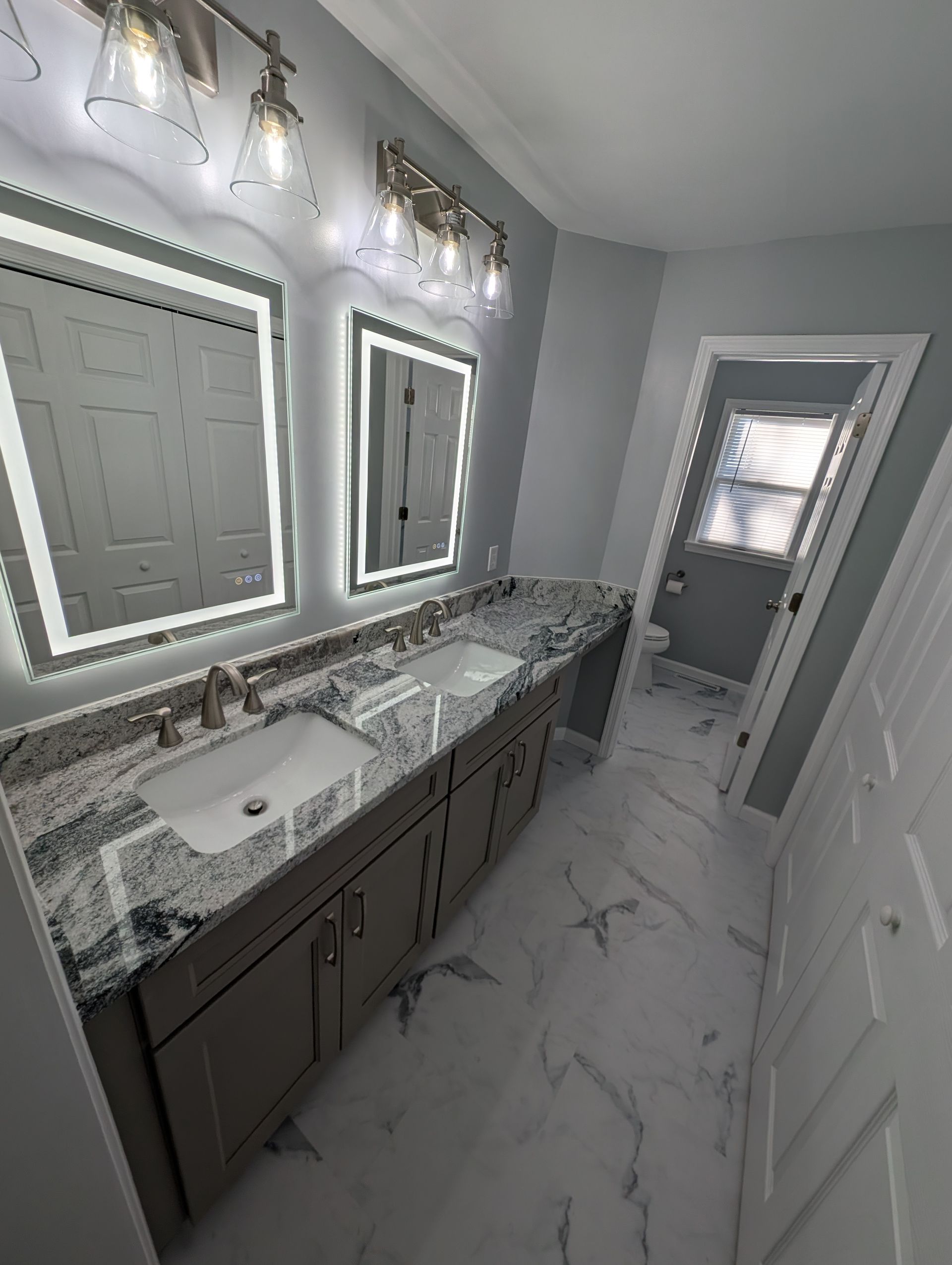 Modern white bathroom with double sinks and LED lighting.
