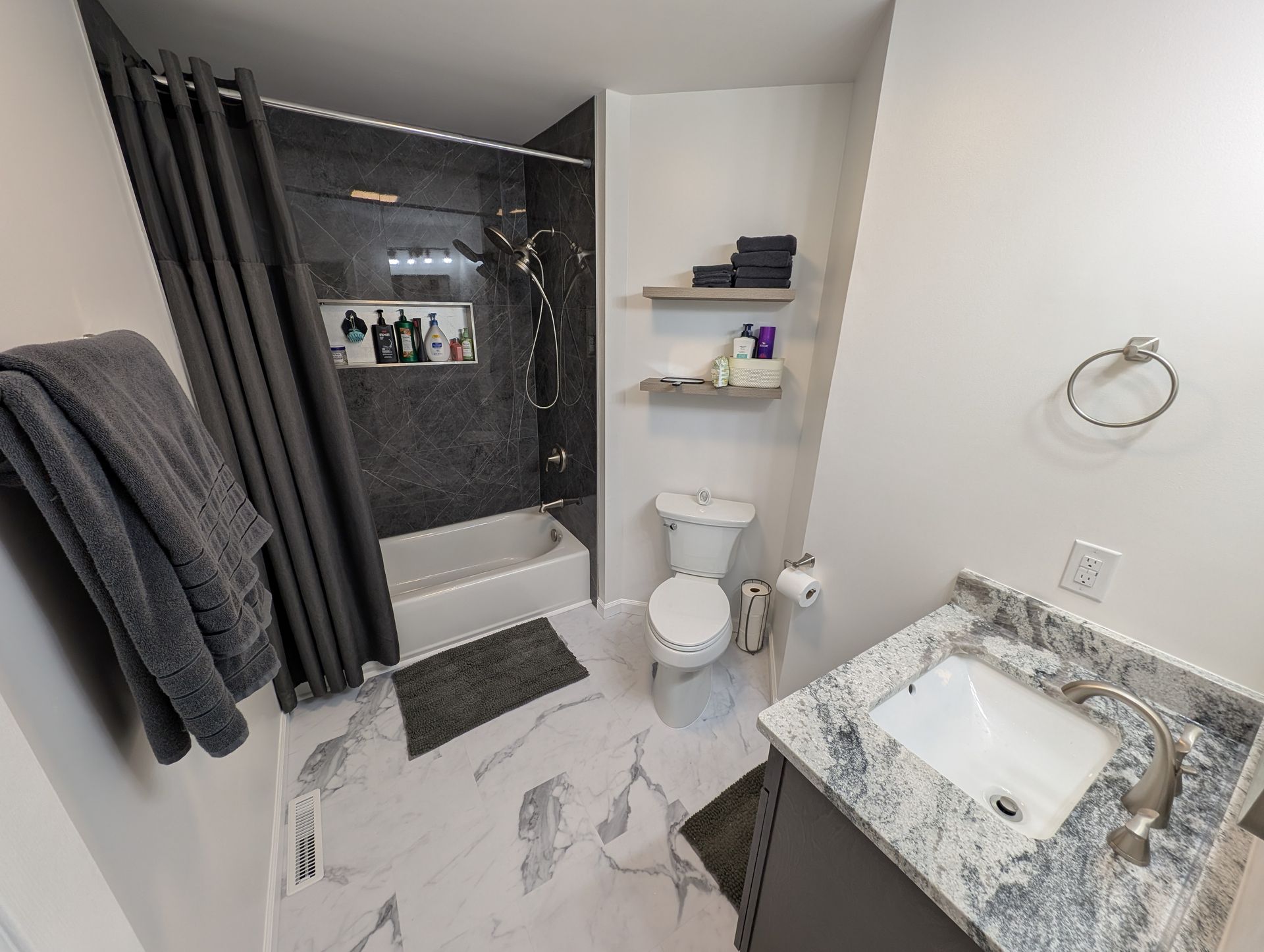 Bathroom with marble-look floor, grey accents, and a shower.