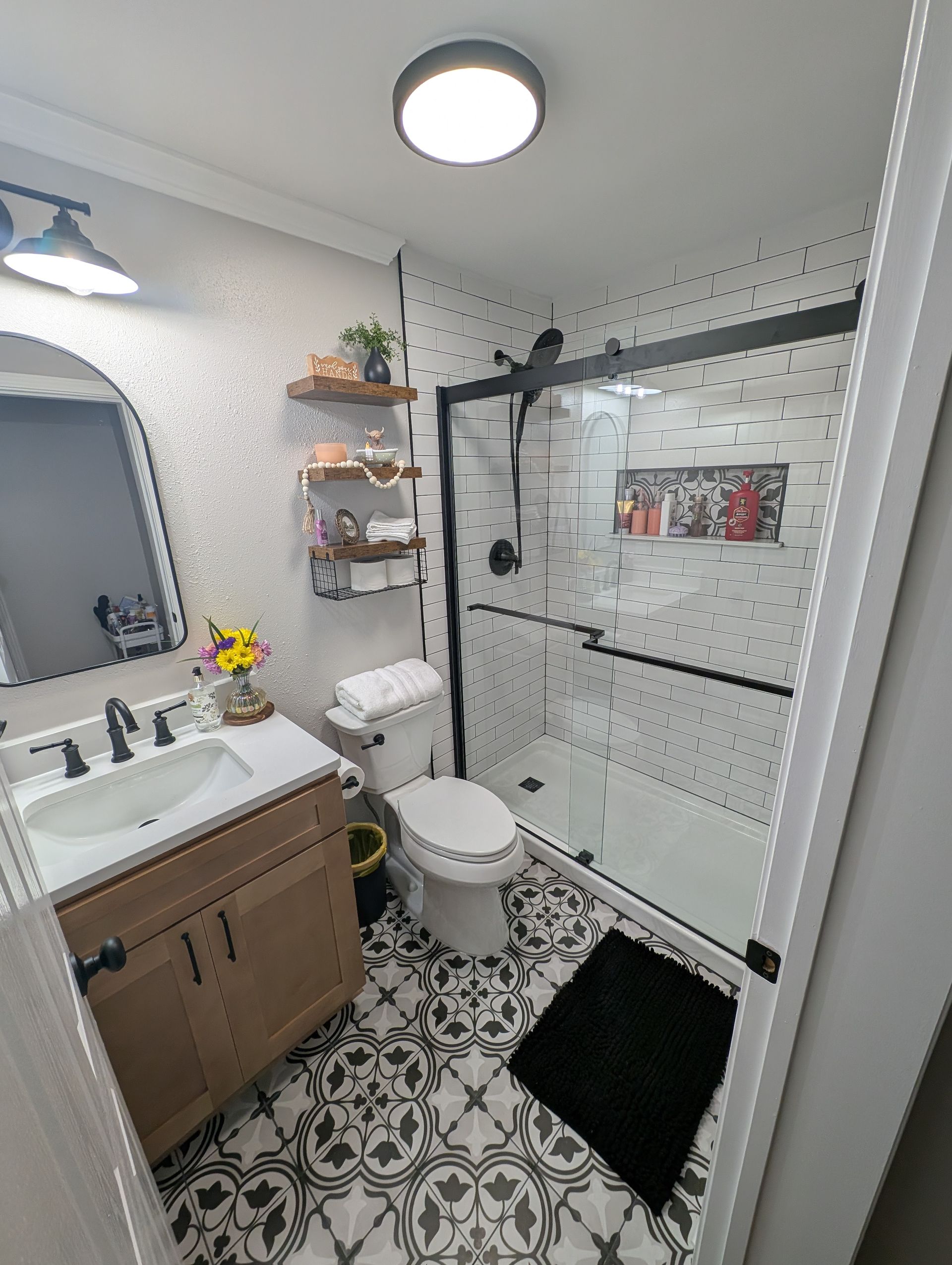Newly renovated bathroom with patterned tiles and black-framed shower.