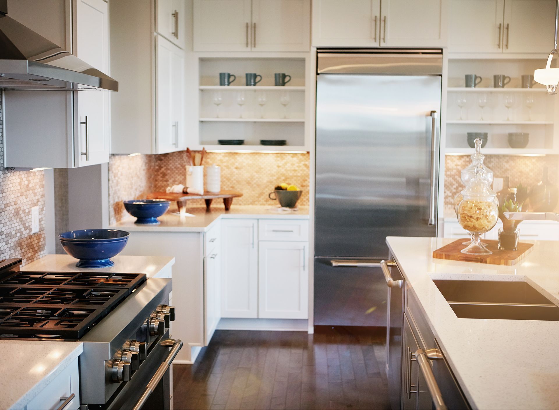 Modern kitchen with white cabinets, stainless steel appliances, a gas stove, and a marble countertop with blue bowls.