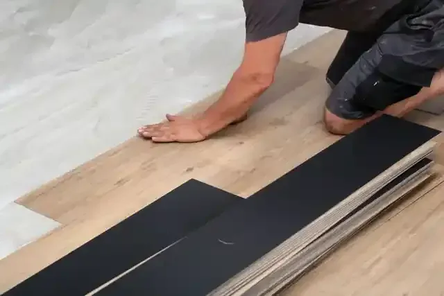 Person kneeling and aligning dark vinyl planks during installation