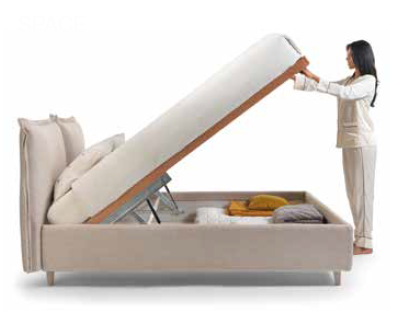 Una donna solleva un materasso beige di un divano letto per rivelare uno spazio contenitore sottostante.
