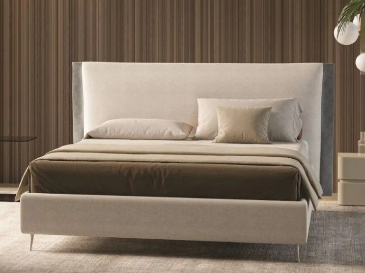 Moderno letto imbottito beige con cuscini e coperta in una camera da letto a righe.