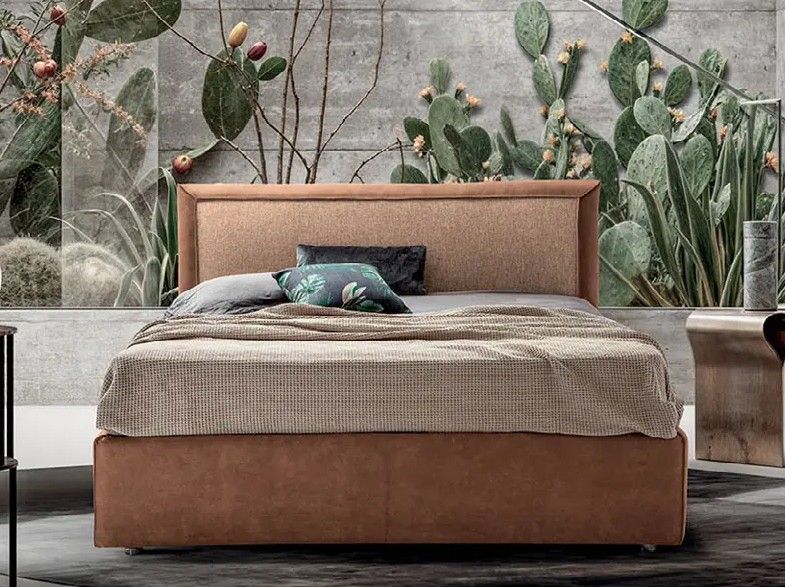 Letto moderno con testiera imbottita beige in una stanza con quadro a parete a tema cactus e arredamento neutro.
