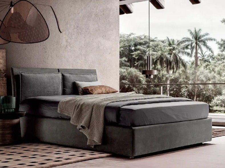 Letto moderno grigio con coperta testurizzata in una camera da letto minimalista con vista sulle palme.