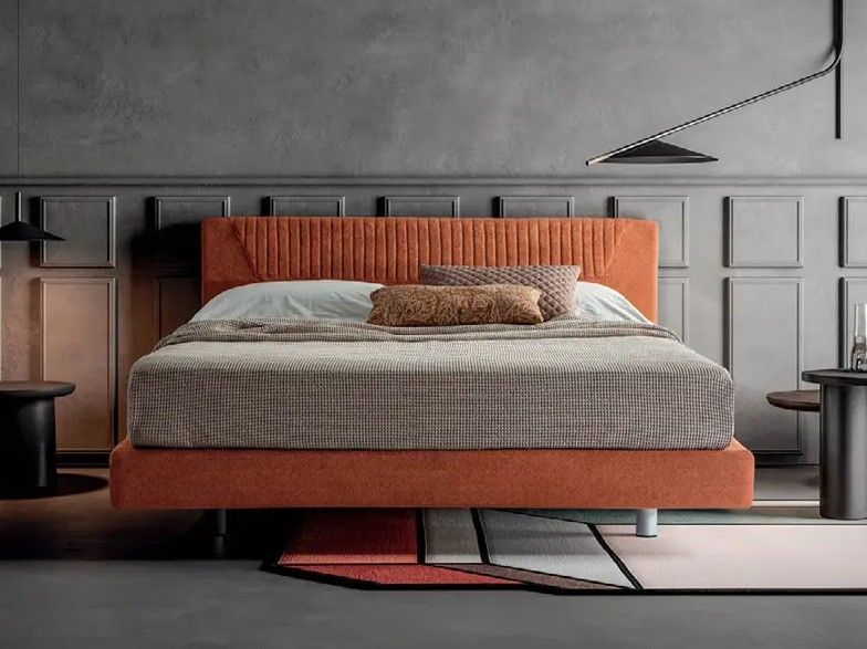 Camera da letto moderna con letto basso arancione, biancheria da letto grigia con trama e pareti rivestite in legno.