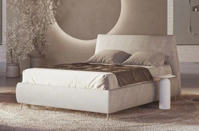 Camera da letto minimalista sui toni del beige con letto imbottito, specchio rotondo a parete e arredamento neutro.