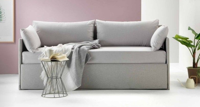 Moderno divano grigio con coperta e tavolino in un soggiorno minimalista.