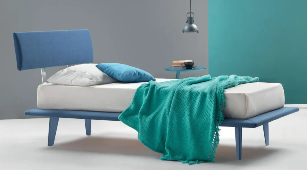 Letto minimalista blu e bianco con coperta color verde acqua in una camera da letto moderna.