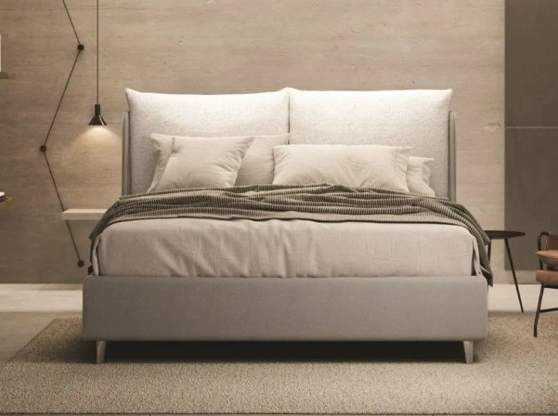 Camera da letto minimalista con letto imbottito bianco, biancheria da letto neutra e pareti color beige caldo.