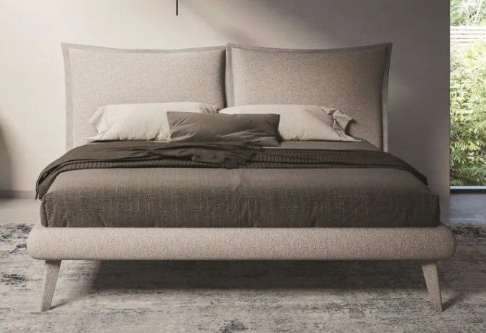 Letto imbottito moderno con lenzuola e cuscini grigi in una camera da letto dai toni neutri.