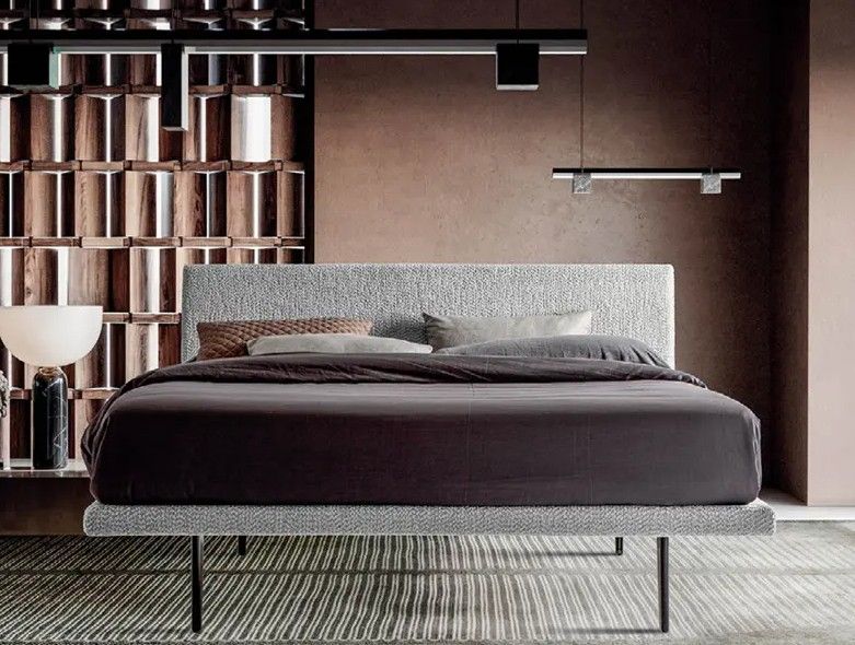 Camera da letto moderna con letto a piattaforma scuro, pannello a parete decorato e lampada da terra nei toni caldi del marrone.
