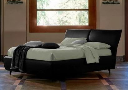Camera da letto moderna con letto nero, lenzuola bianche e una grande finestra alle spalle.