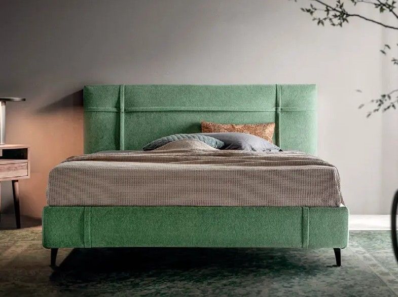 Letto imbottito verde con lenzuola grigie in una camera da letto moderna