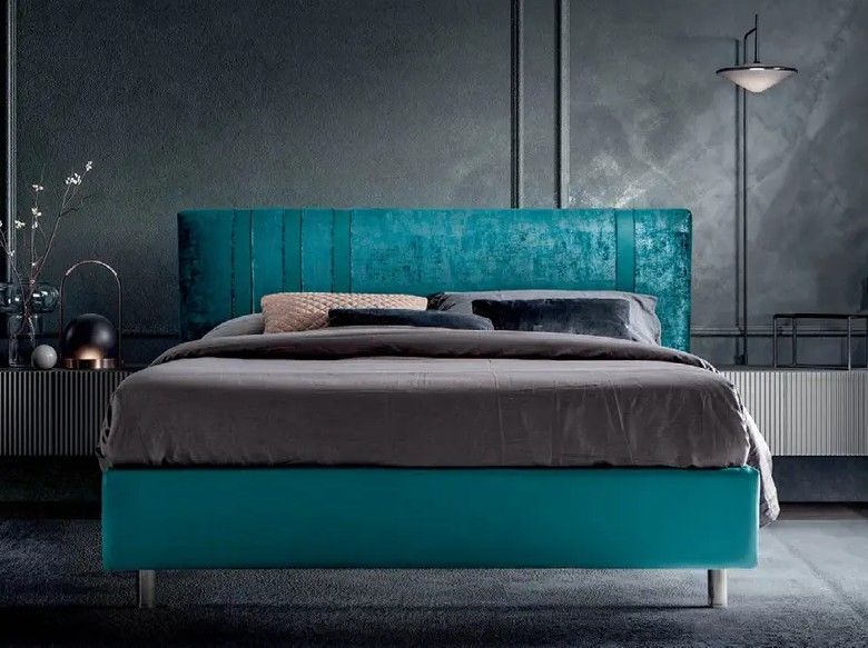 Camera da letto moderna con letto imbottito turchese e biancheria da letto grigia su una parete scura