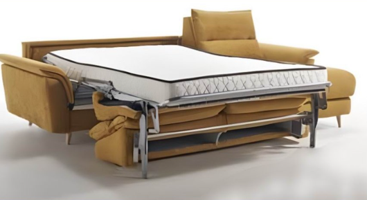 Divano letto trasformabile con materasso a vista, rivestimento color giallo senape e struttura in metallo su sfondo bianco.